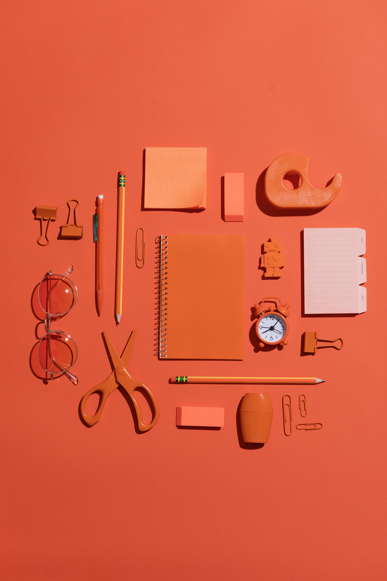 Orange stationery laid out on an orange surface.